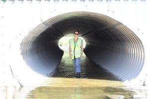Sarah Schacher, P.E., completes a final inspection of the Valdez Tidal Flats Culvert Replacement in Valdez, Alaska. The depressed culverts, designed by Schacher and her team, accommodate the fish population in the tidal flats.