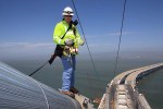 Photographer Bill Hall captured Caltrans Transportation Engineer Matt Bruce inspecting the cable band installation of the San Francisco-Oakland Bay Bridge. American Bridge Fluor completed the cable band installation Matt inspected atop the new main cable of the self-anchored suspension structure.