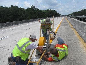 Richie Morehouse really puts his back into his work as his colleagues with Jenkins Painting, Inc., Ryan Manfready and Matt Hendricks, work to get the thermoplastic down on a Florida Department of Transportation resurfacing project on Interstate 10 in Madison County, Florida.