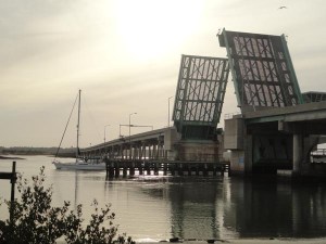 This seems like a scene out of a Robert Frost poem. A sail boat is taking a peaceful trip on the 'road' less traveled under the SR 206 Crescent Beach Bridge in St. Johns County, Florida at sunset.
