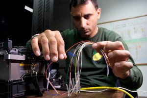 Sam Sakran, FDOT District Four maintenance contractor, carefully gathers the ends of fiber optic to be spliced together.