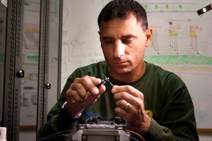 Sam Sakran, FDOT District Four maintenance contractor, carefully gathers the ends of fiber optic to be spliced together.