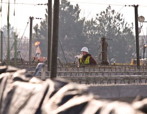A lone worker stands amid girders during overpass construction in Boise, Idaho.