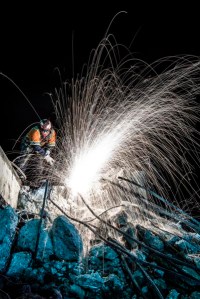 An unknown worker cuts through re-enforcing rebar in the concrete rubble of a demolished bridge on State Route Four in Antioch Ca. The bridge was demolished to make room for the widening of the Highway and the addition of a light rail system.