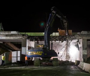 A large excavator fitted with a hydraulic hammer breaks down a section of  concrete bridge on State Route Four in Antioch Ca. The bridge was demolished to make room for the widening of the highway and the addition of a light rail system.