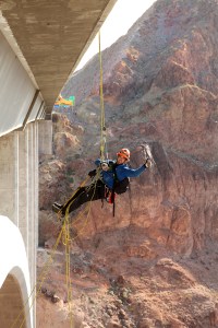 Trask Bradbury of Gemini Rope Solutions gives the thumbs-up while rapelling off the Mike O'Callaghan-Pat Tillman Memorial Bridge (Hoover Dam Bypass) during a routine biennial bridge inspection. The concrete-steel composite arch bridge looms 840 feet above the Colorado River and is the 2nd largest bridge in the United States at 1,900 feet in length.