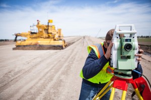 Work continues and a grader passes along the new bypass near Kearney, Nebraska, as a worker surveys the grade.